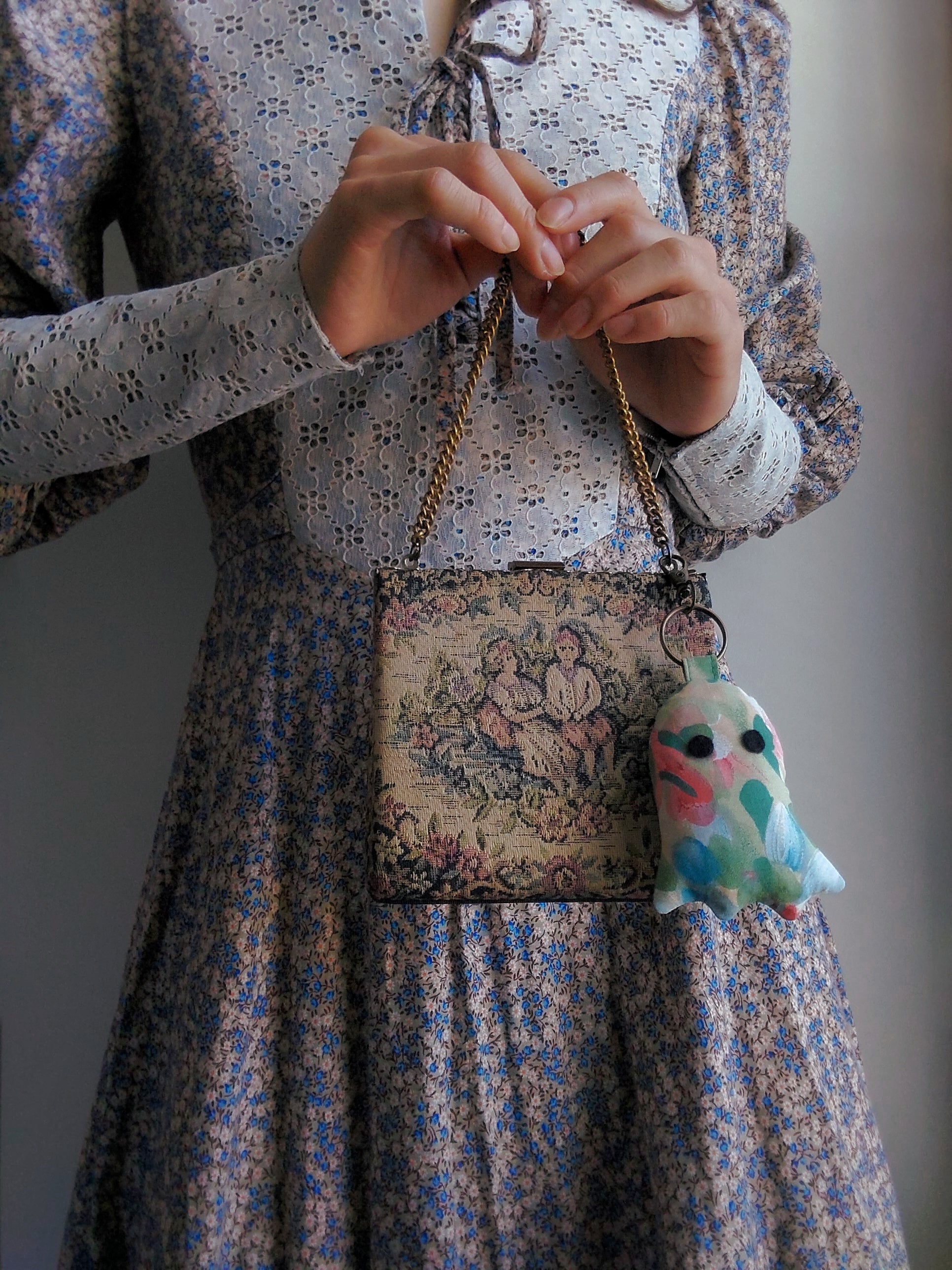 front view of cotton upcycled ghost keychain displayed on purse held by model