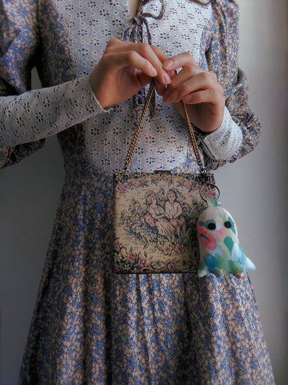 front view of cotton upcycled ghost keychain displayed on purse held by model