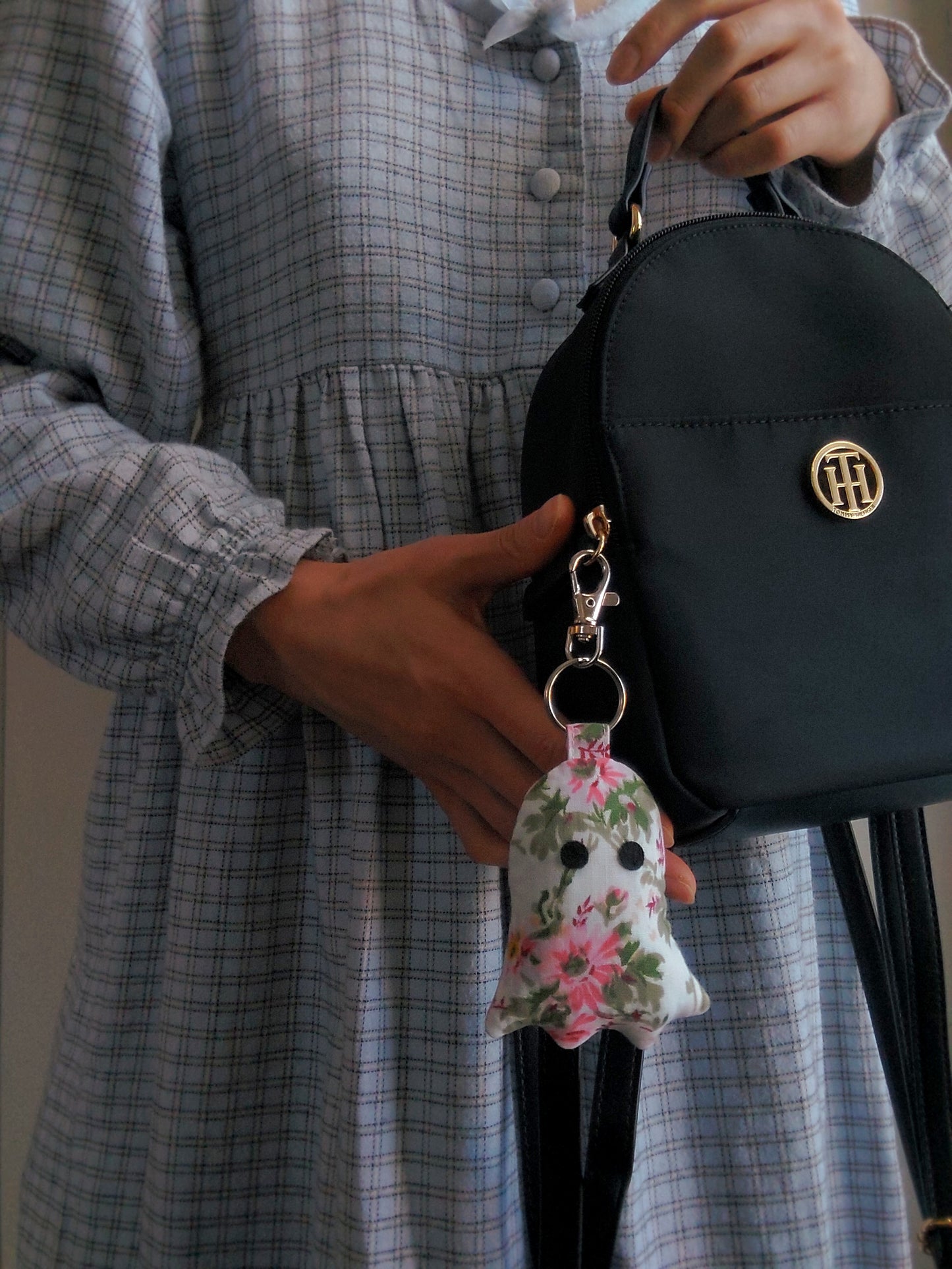 front view of pink floral upcycled ghost keychain displayed on purse held by model