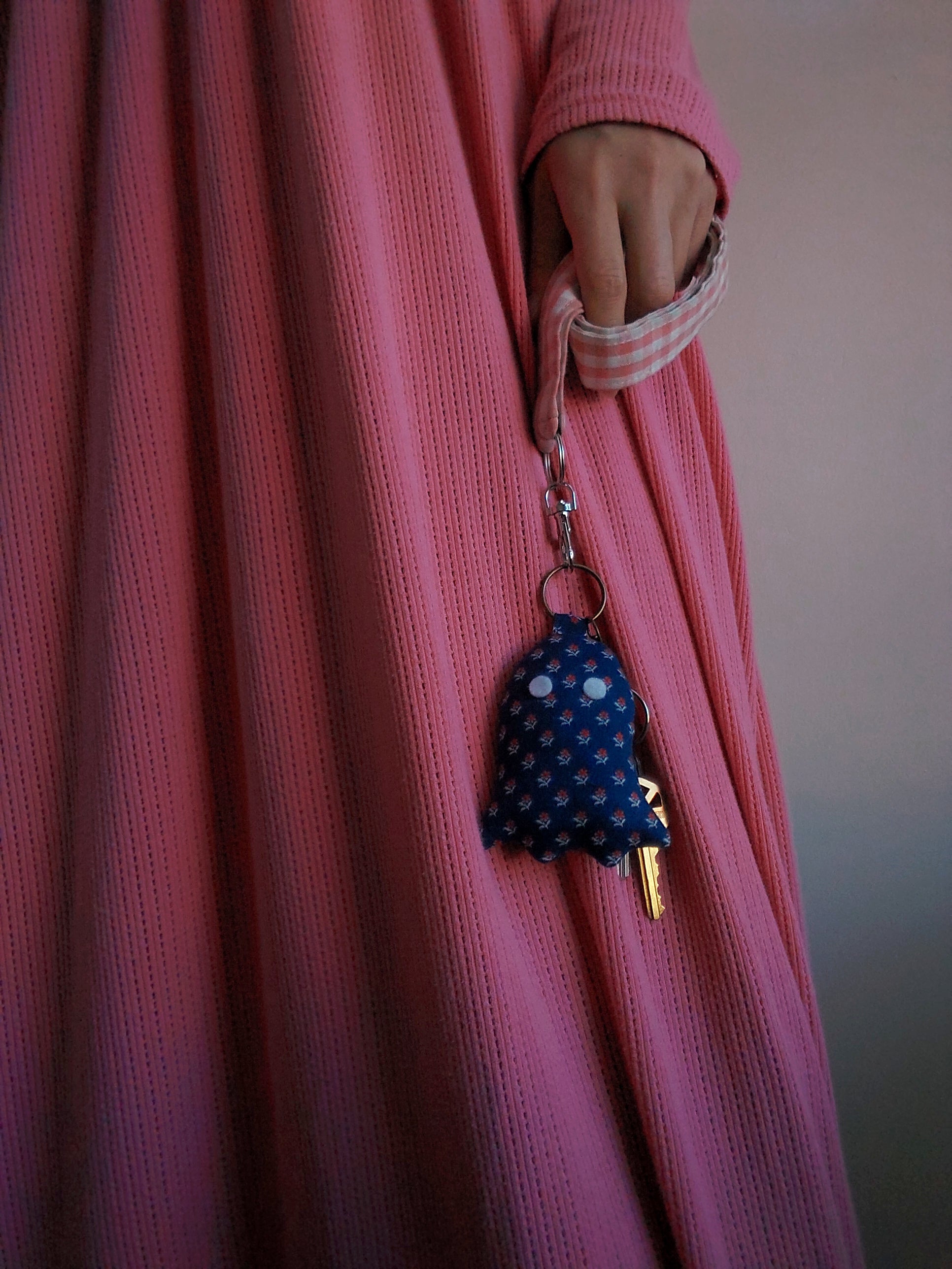 front view of calico navy cotton upcycled ghost keychain displayed on keys held by model