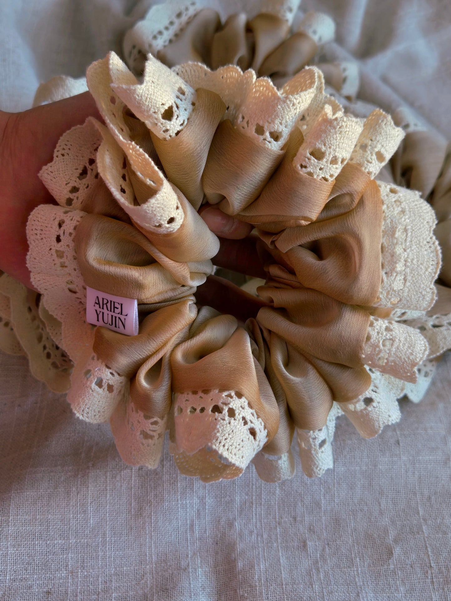 front view of beige lace organza upcycled scrunchie when held