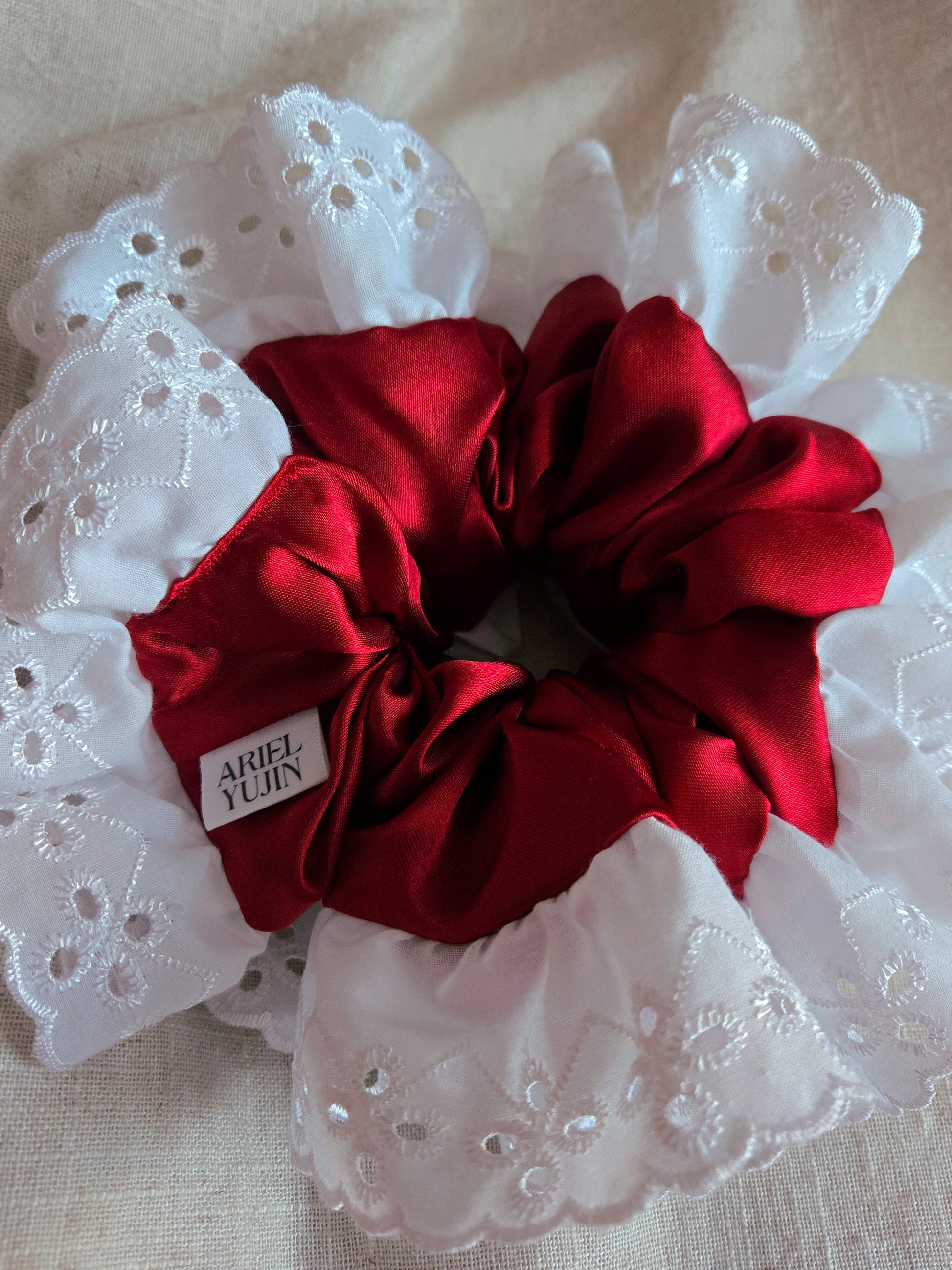 front view of white lace red satin upcycled scrunchie laying down