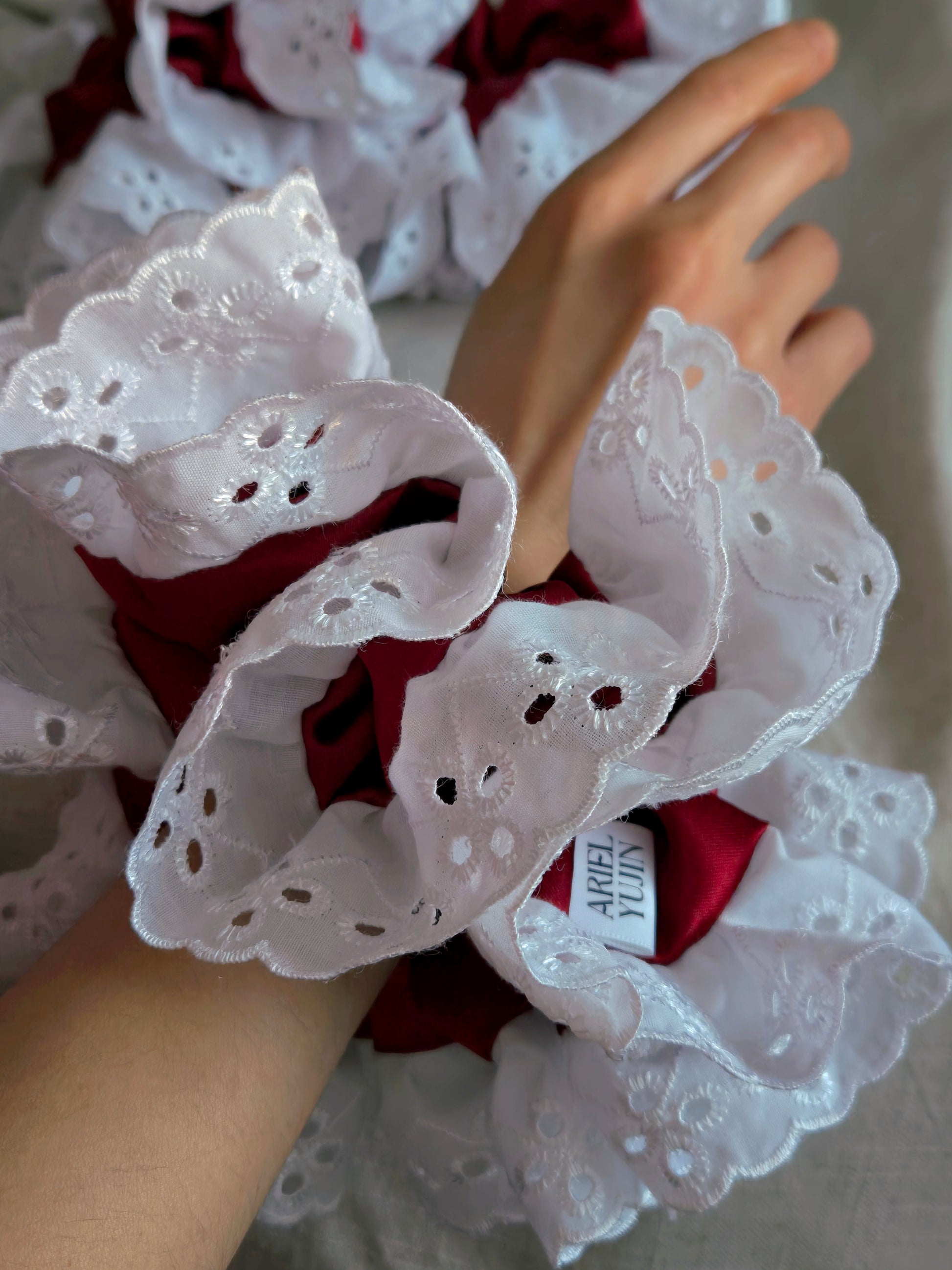 side view of white lace red satin upcycled scrunchie on wrist