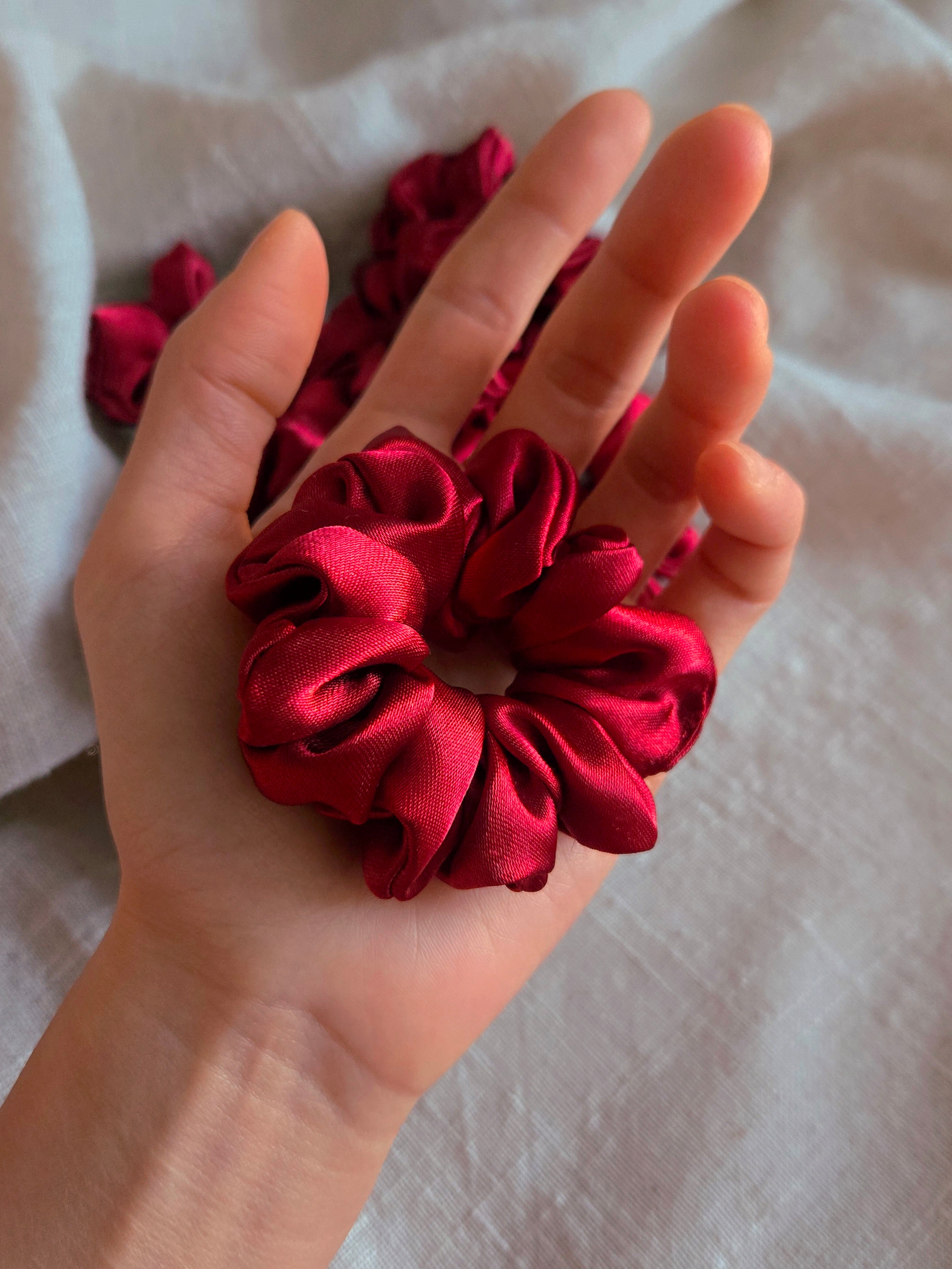 front view of red satin upcycled scrunchies in hand size reference