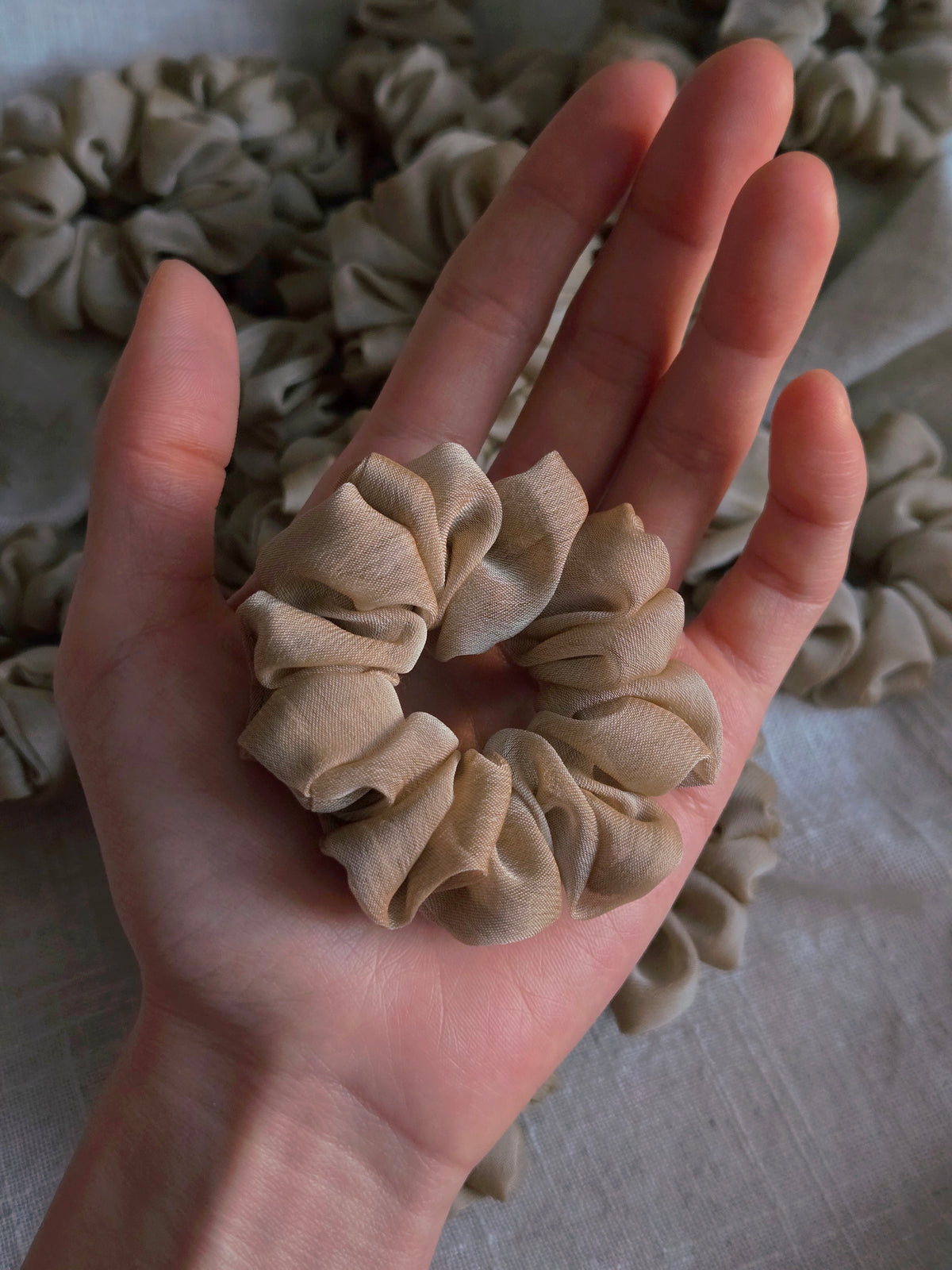 close up of beige organza upcycled scrunchie in hand size reference