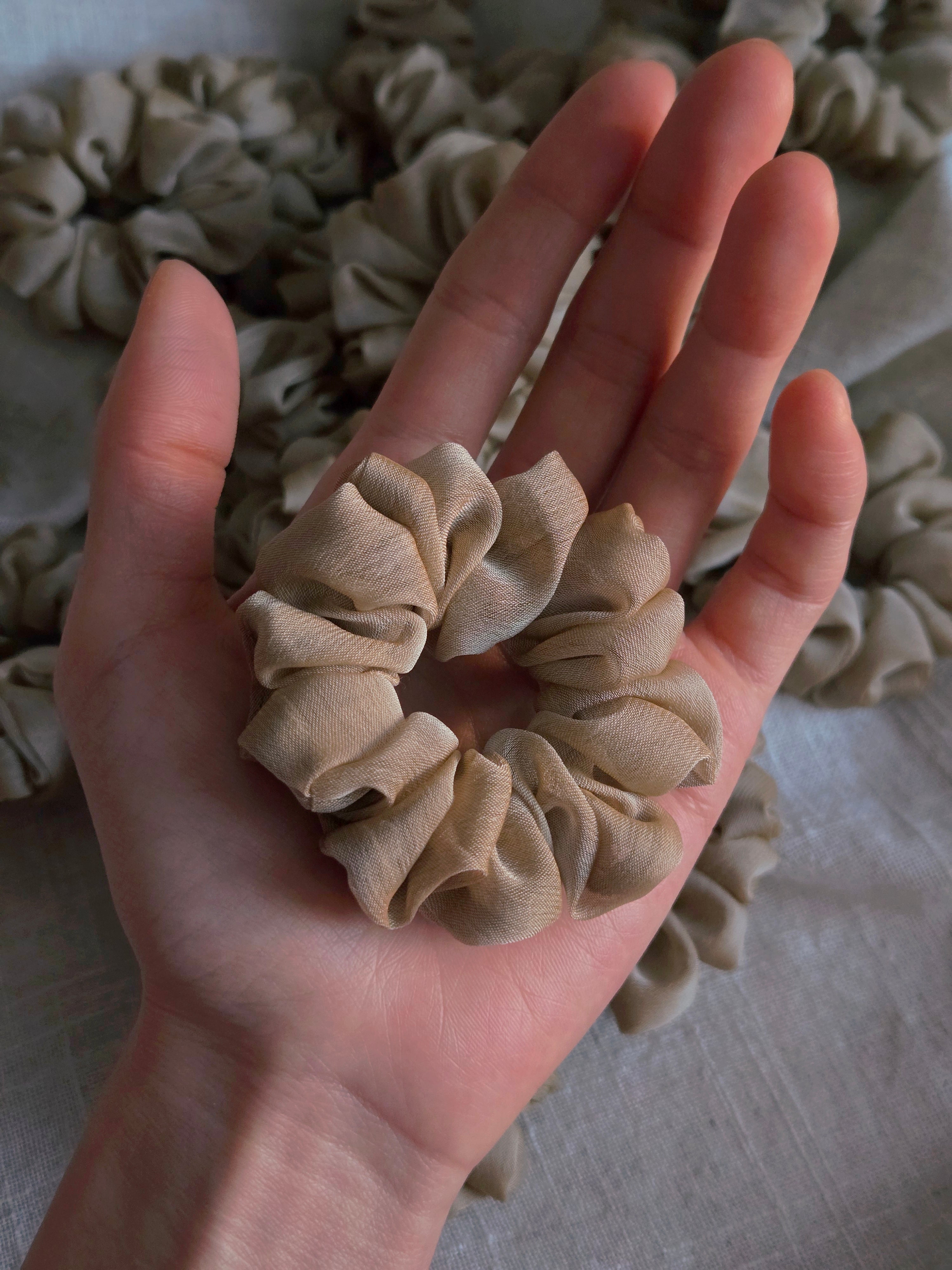 close up of beige organza upcycled scrunchie in hand size reference