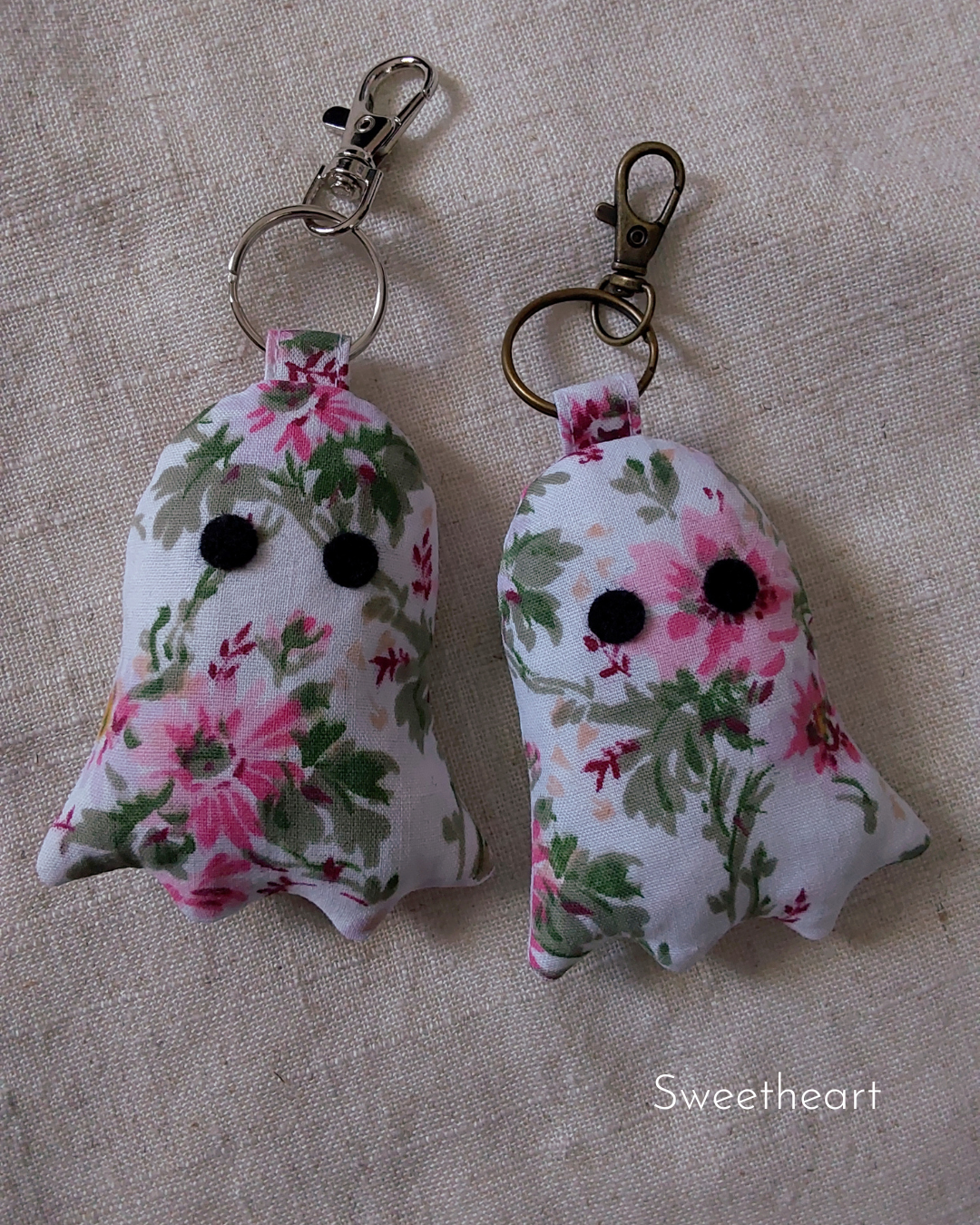 front view of pink flowers white cotton upcycled ghost keychains laying flat