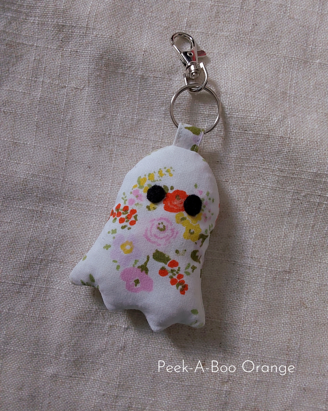 front view of orange floral white cotton upcycled ghost keychains laying flat