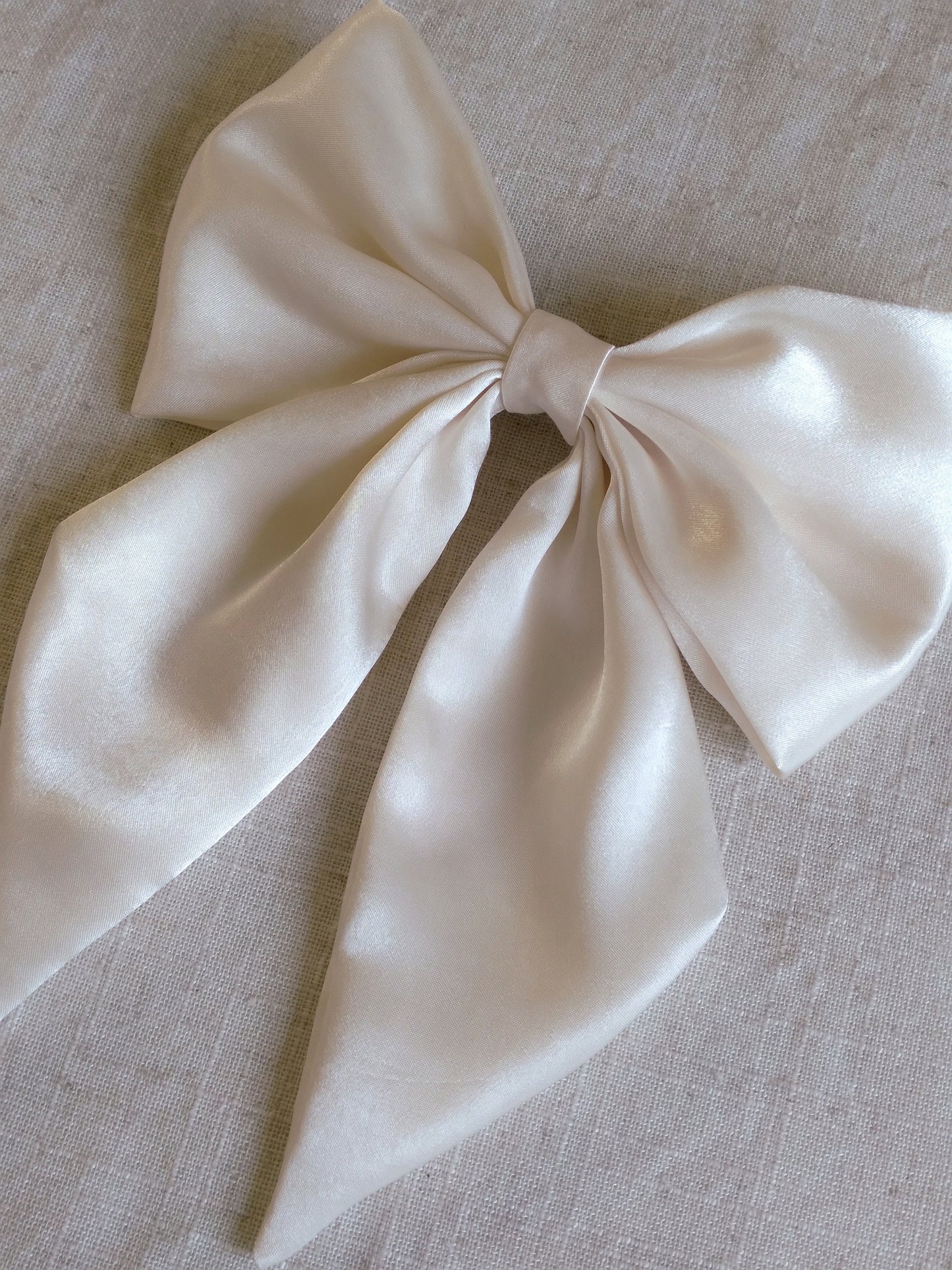 close up of ivory satin upcycled hair bow laying flat