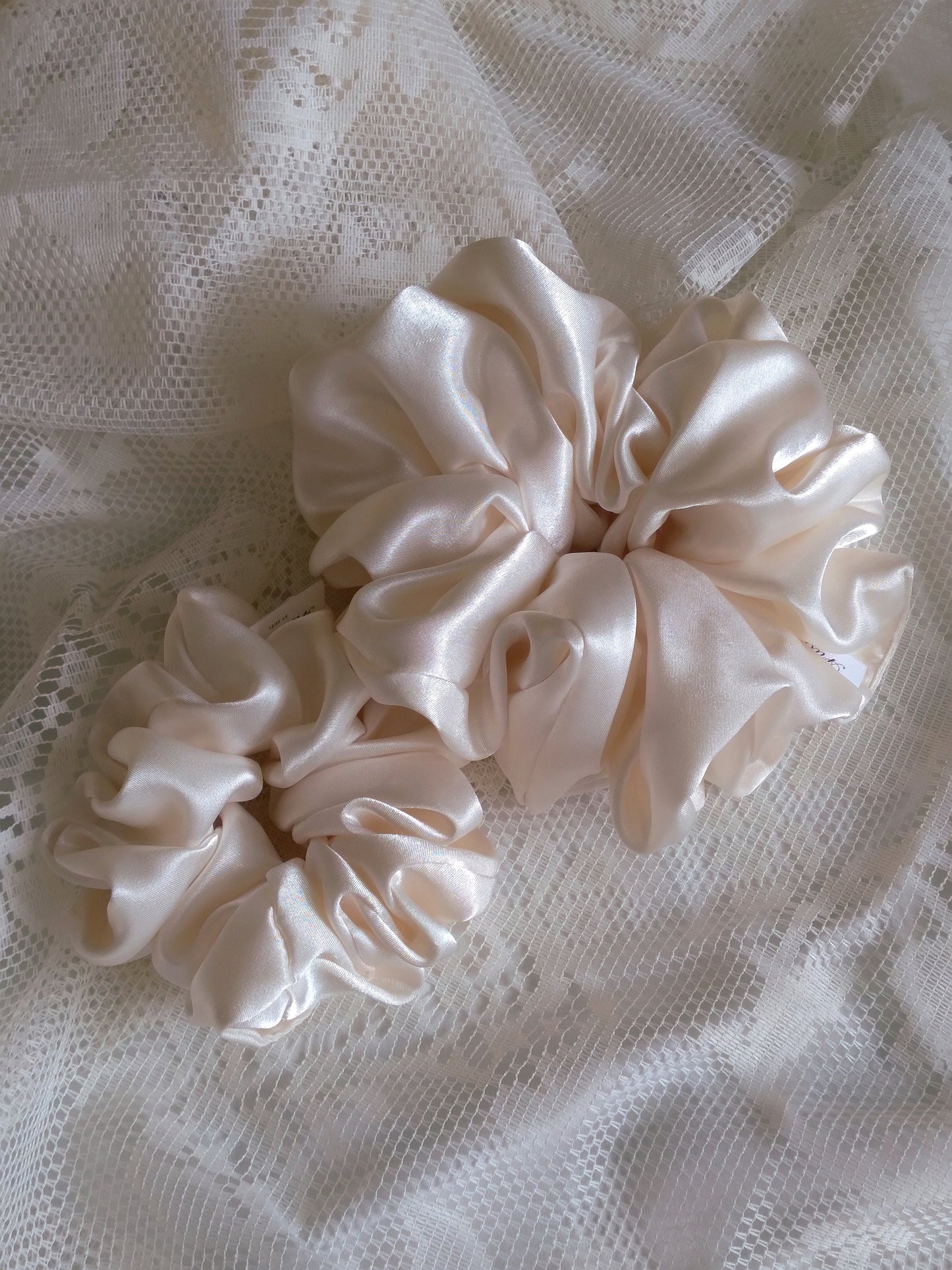 front view of ivory satin upcycled scrunchies laying down size comparison