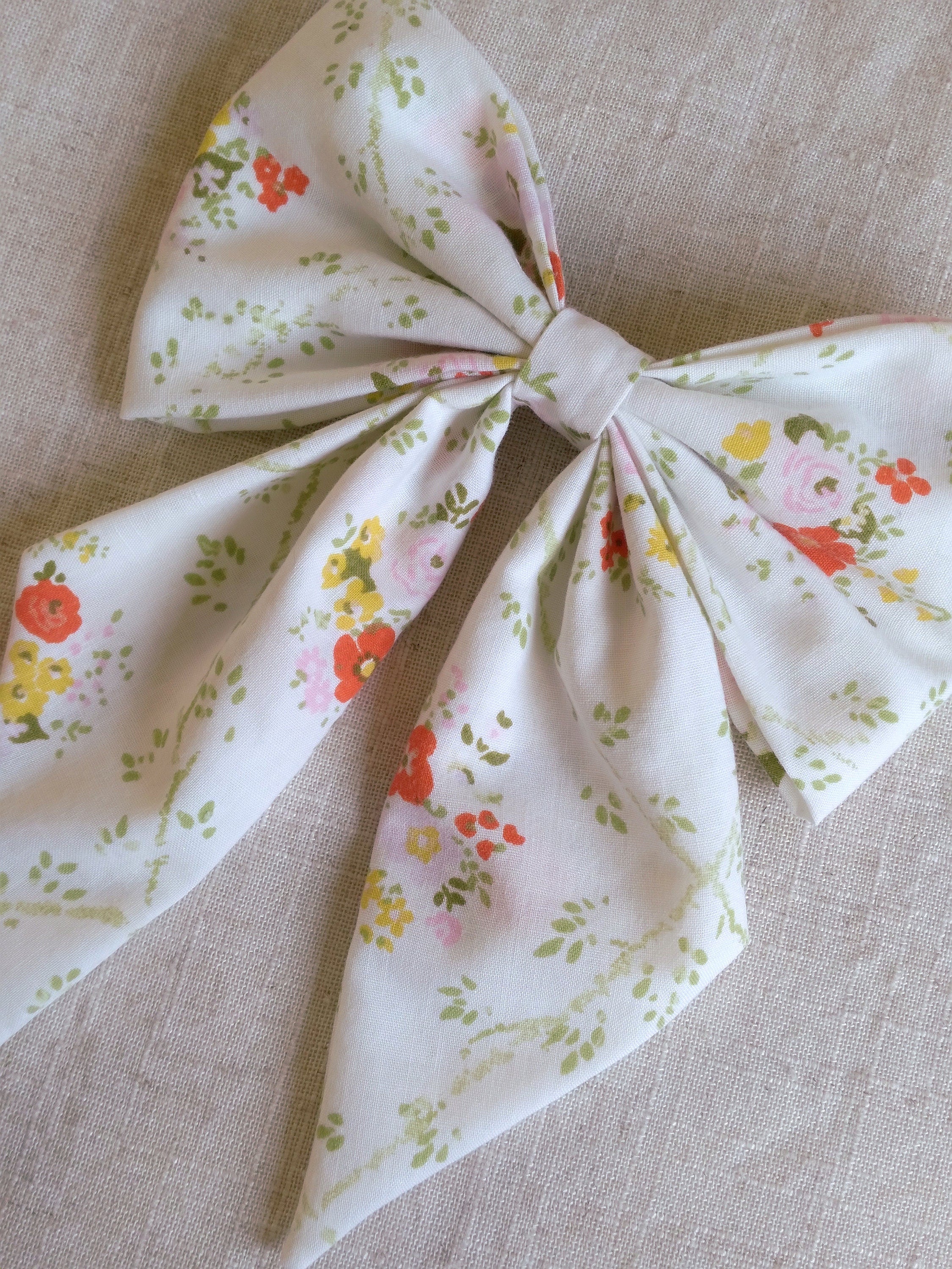 close up of floral white cotton upcycled hair bow laying flat
