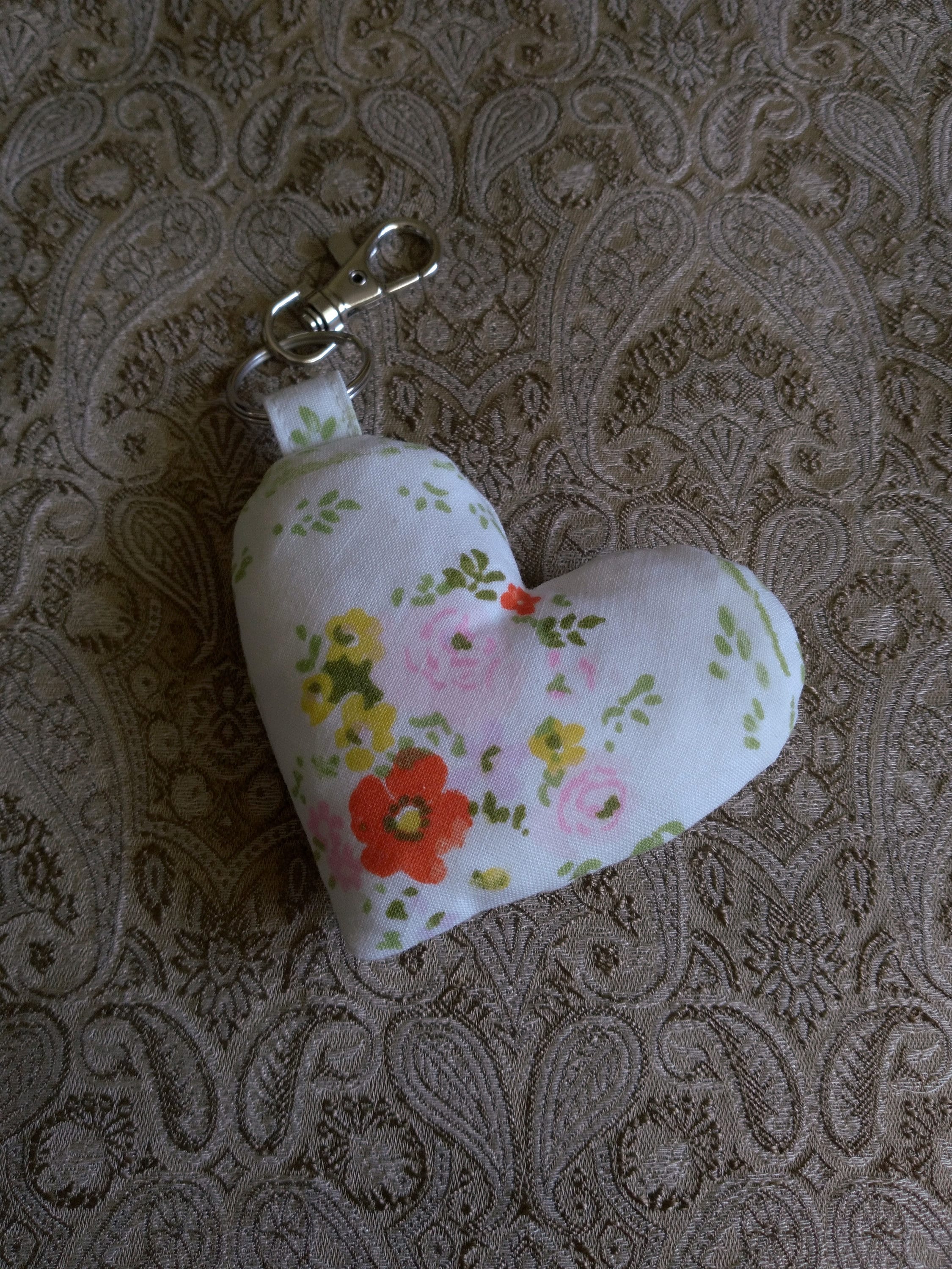 front view of pink yellow orange flowers white upcycled heart keychain laying flat