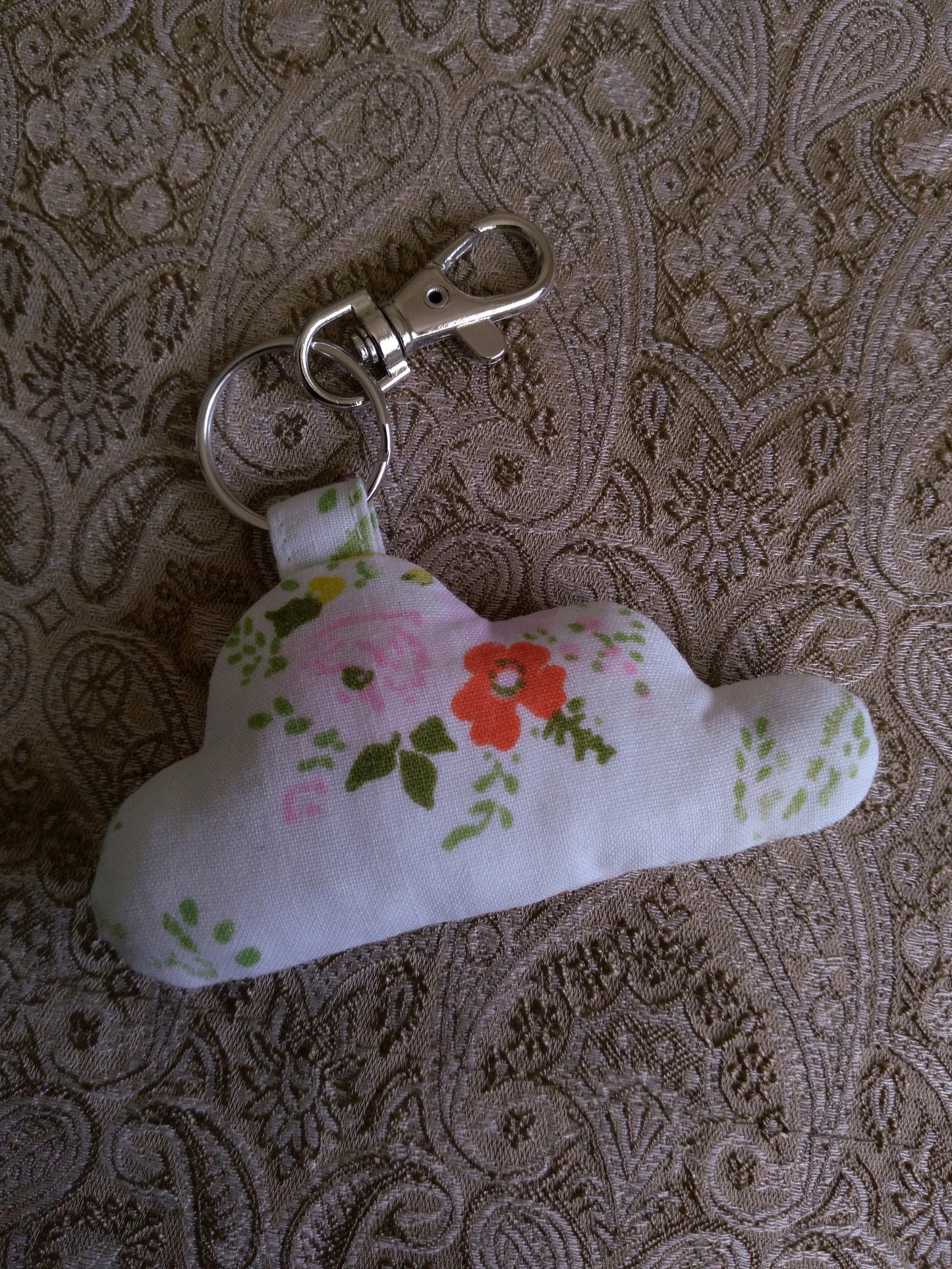 front view of orange pink florals white upcycled cloud keychain laying flat