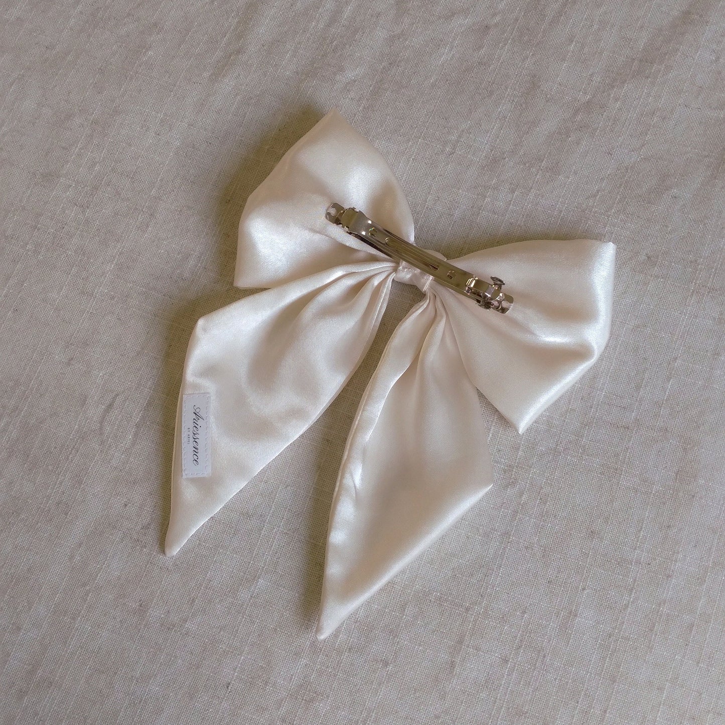 back view of ivory satin upcycled hair bow laying flat