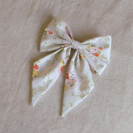 front view of floral white cotton upcycled hair bow laying flat