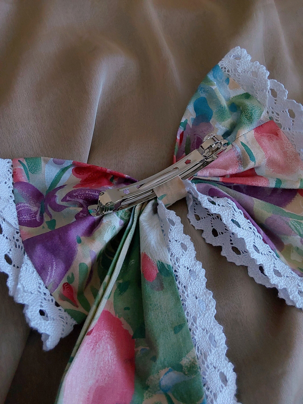 back view of colorful flowers lace cotton upcycled hair bow laying flat