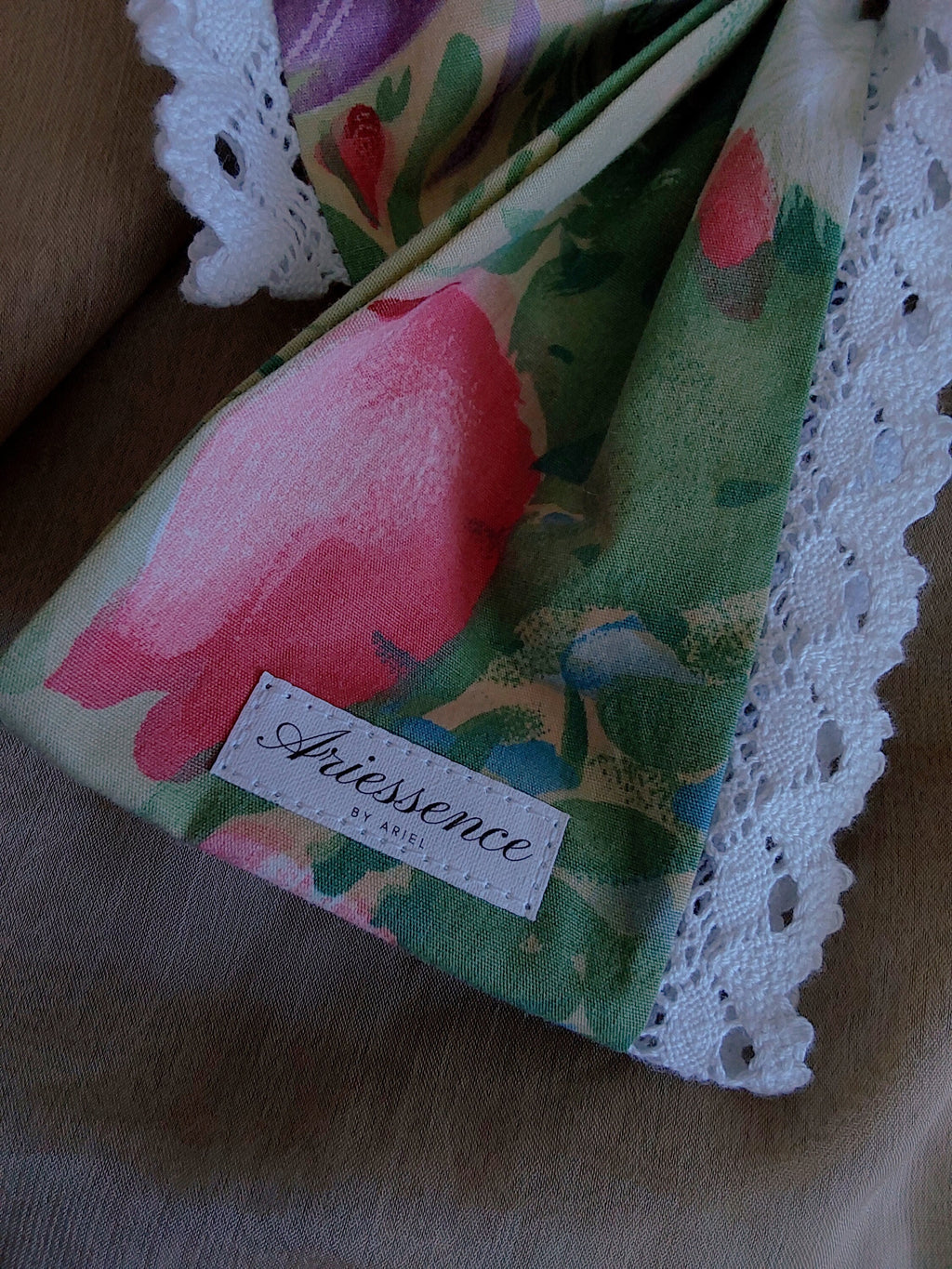 close up of label on colorful flowers lace cotton upcycled hair bow laying flat